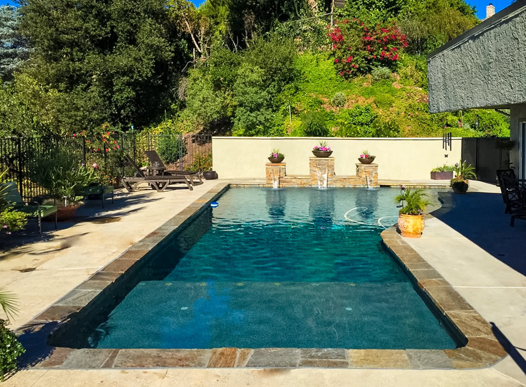 A swimming pool remodel by The Pool Pro. Pebble finish, added lighted water features, sun shelf, new coping, new plumbing, new equipment, new light.
