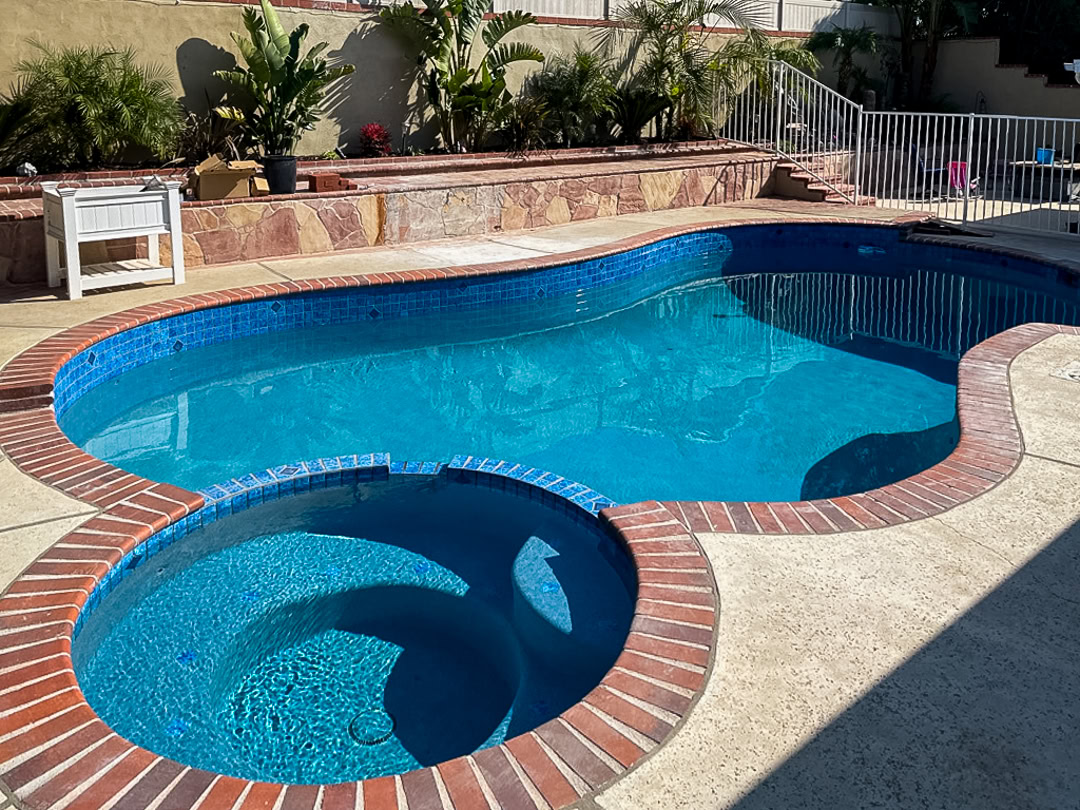 A swimming pool remodel by The Pool Pro. Removal of large rock waterfall, pebble finish, new tile, new autofill, new lights.