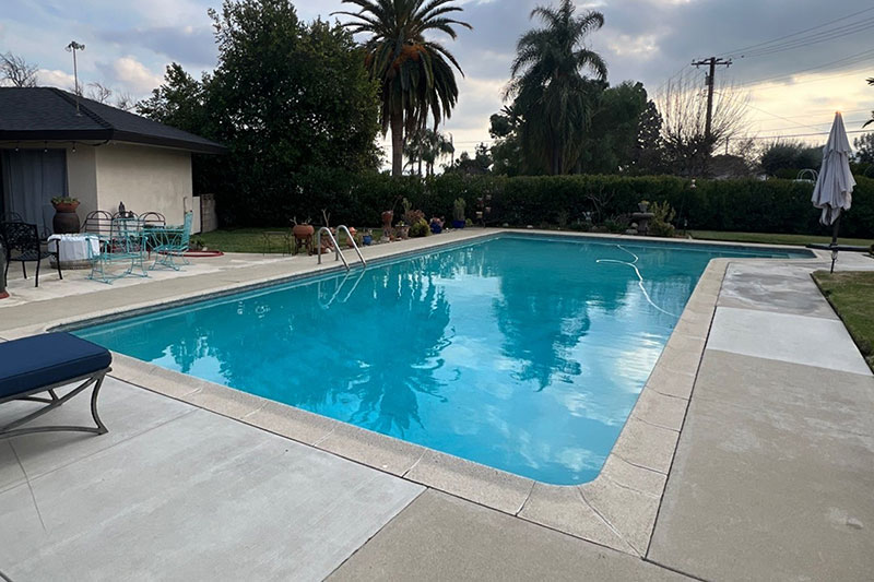 Beautiful backyard swimming pool with clear water and surrounding patio.